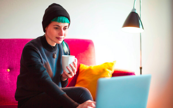 Woman with green hair looking at a laptop