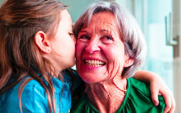 Grandchild kissing her grandmother on the cheek