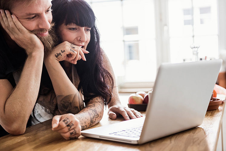 Young couple look at a laptop together.