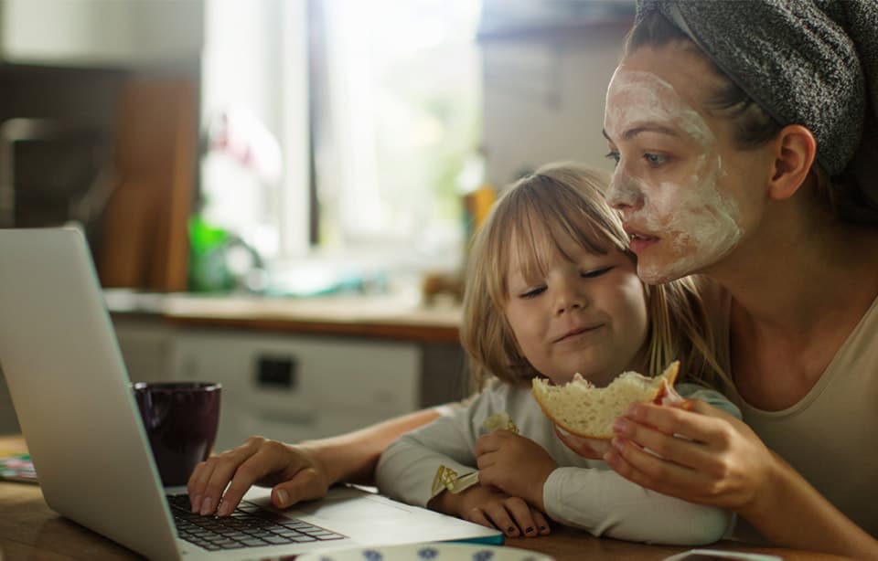 A mother and child sitting together whilst looking at a laptop.