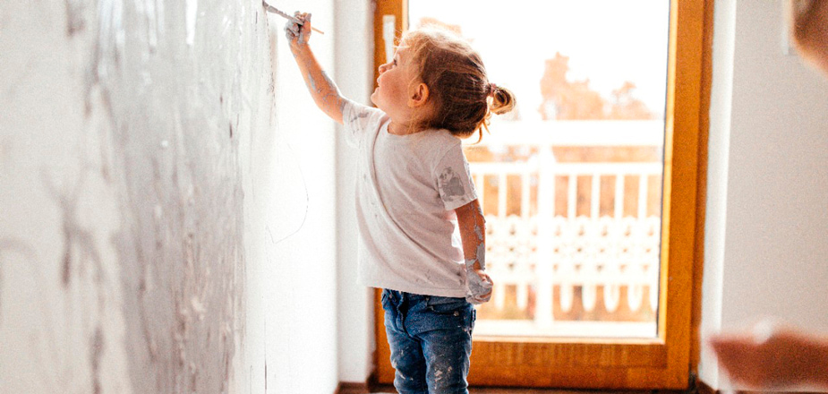 Little girl painting on wall