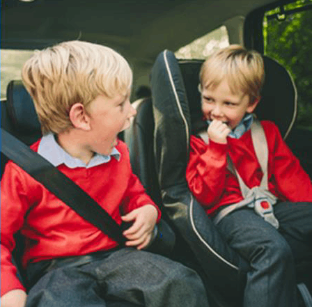 two children sat in the back of the car laughing together