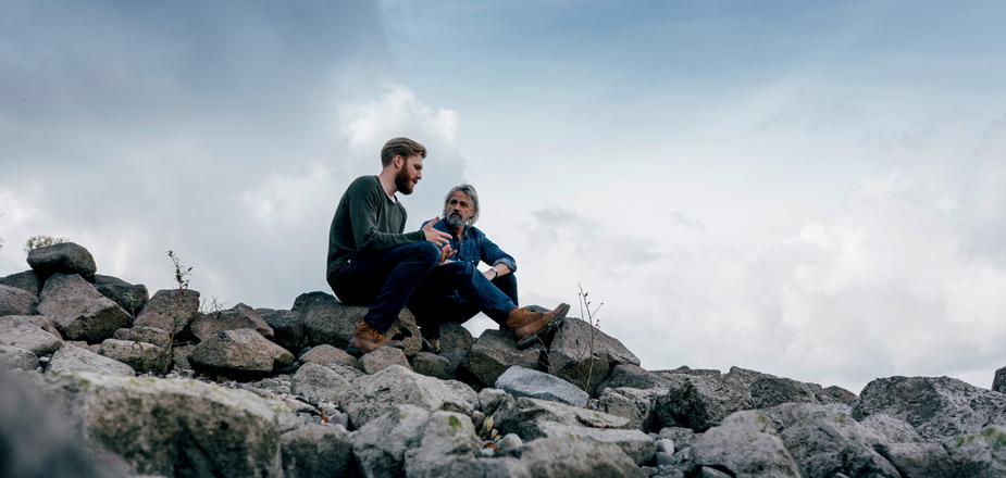 Two men sitting on rocks.