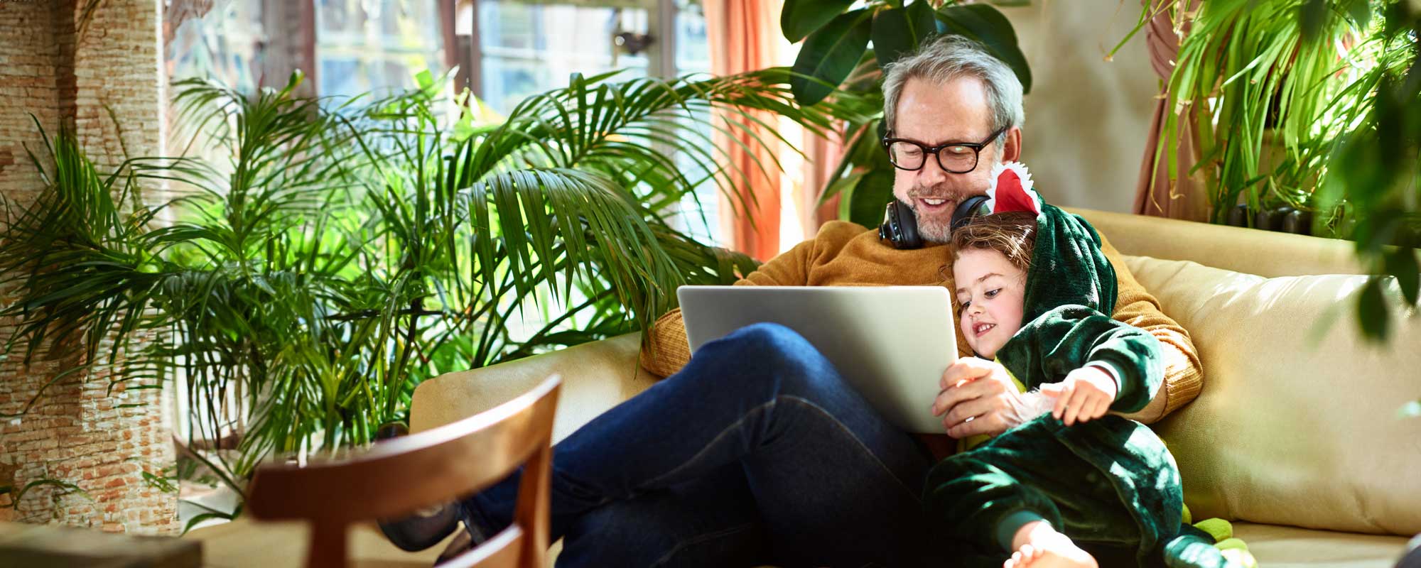 Man sitting with a child on a sofa looking at a tablet