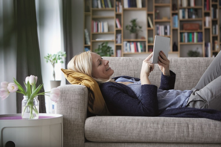 Lady laying on sofa using a tablet