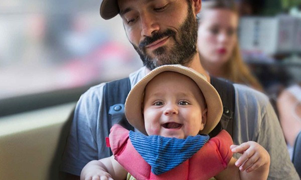 An image of a young man and baby sitting on a bus.