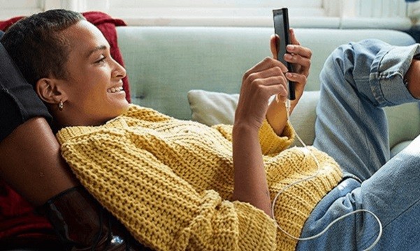 Image of a lady on her couch, relaxing and looking at her phone.